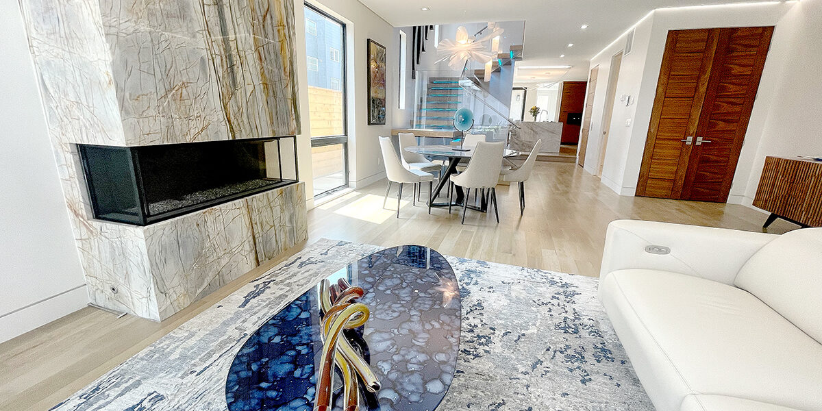 interior view of ultra modern home with fireplace, blue glass coffee table and view into the kitchen.