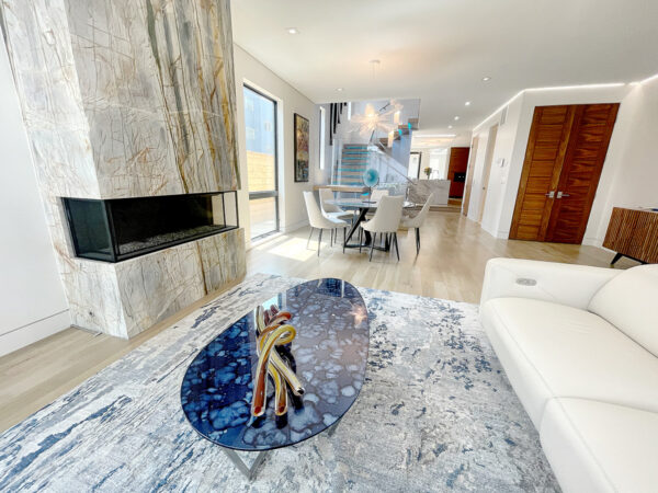 interior view of ultra modern home with fireplace, blue glass coffee table and view into the kitchen.